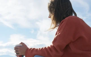 adult on beach drinking coffee